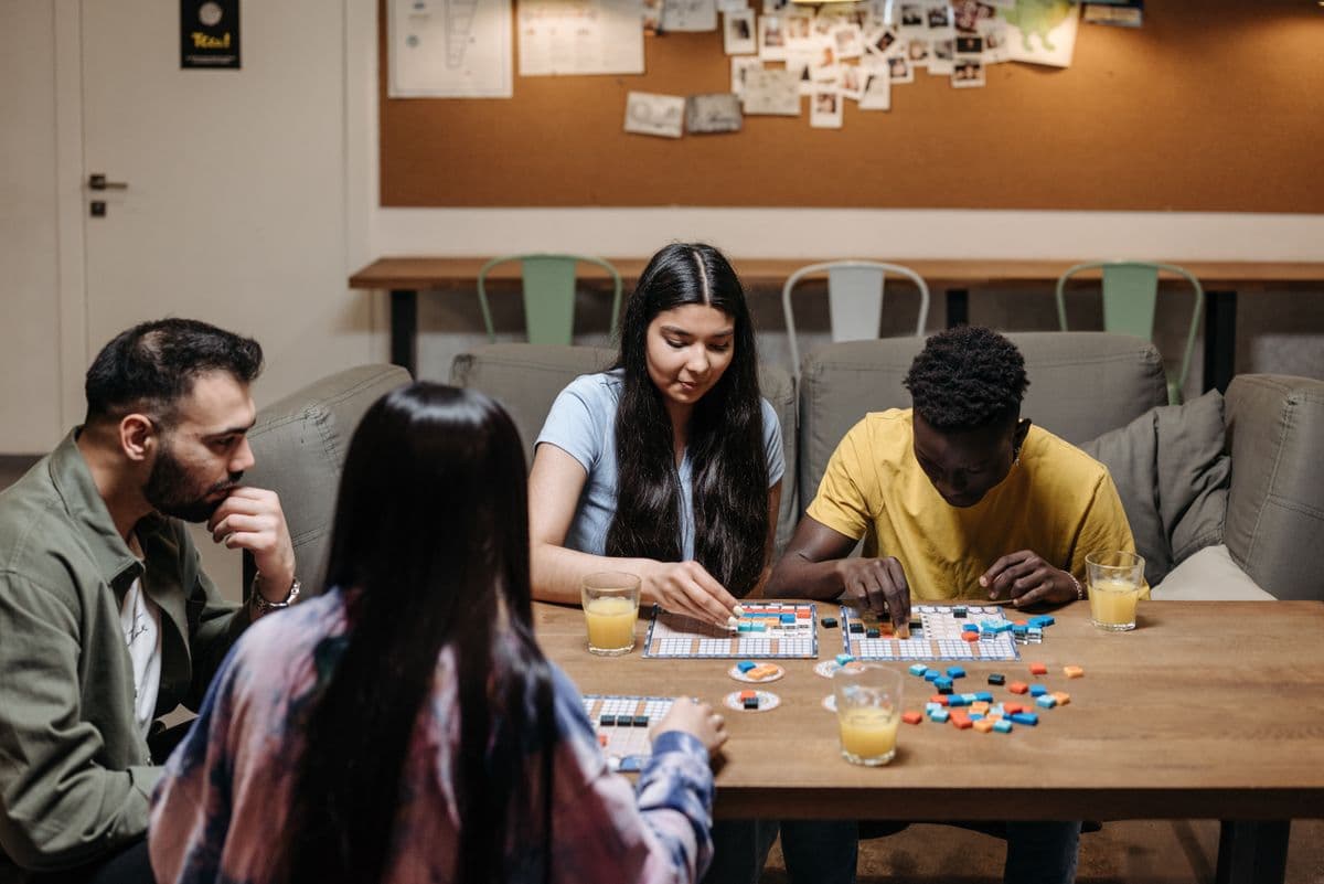 Des amis jouent à un jeu de société autour d'une table en bois